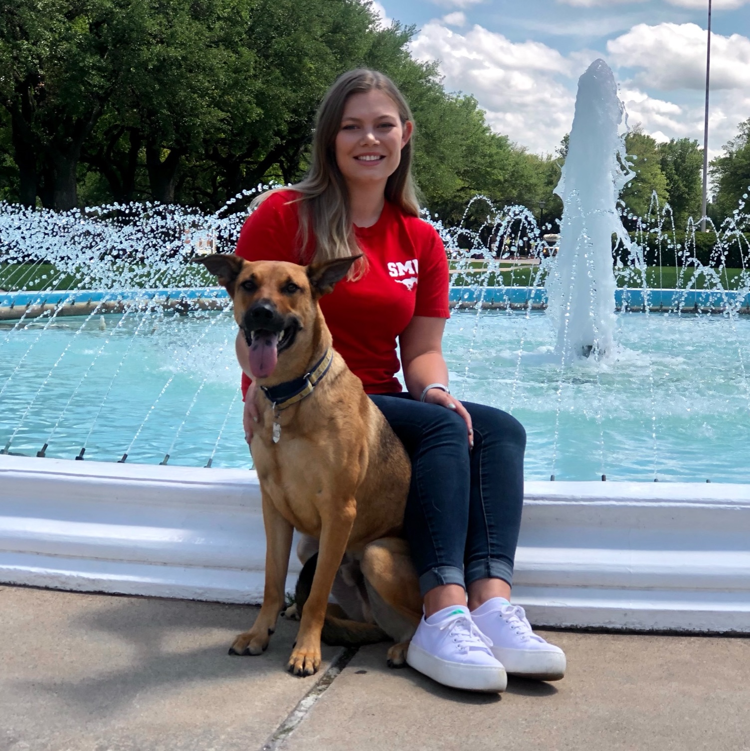 woman poses with dog in front of fountain